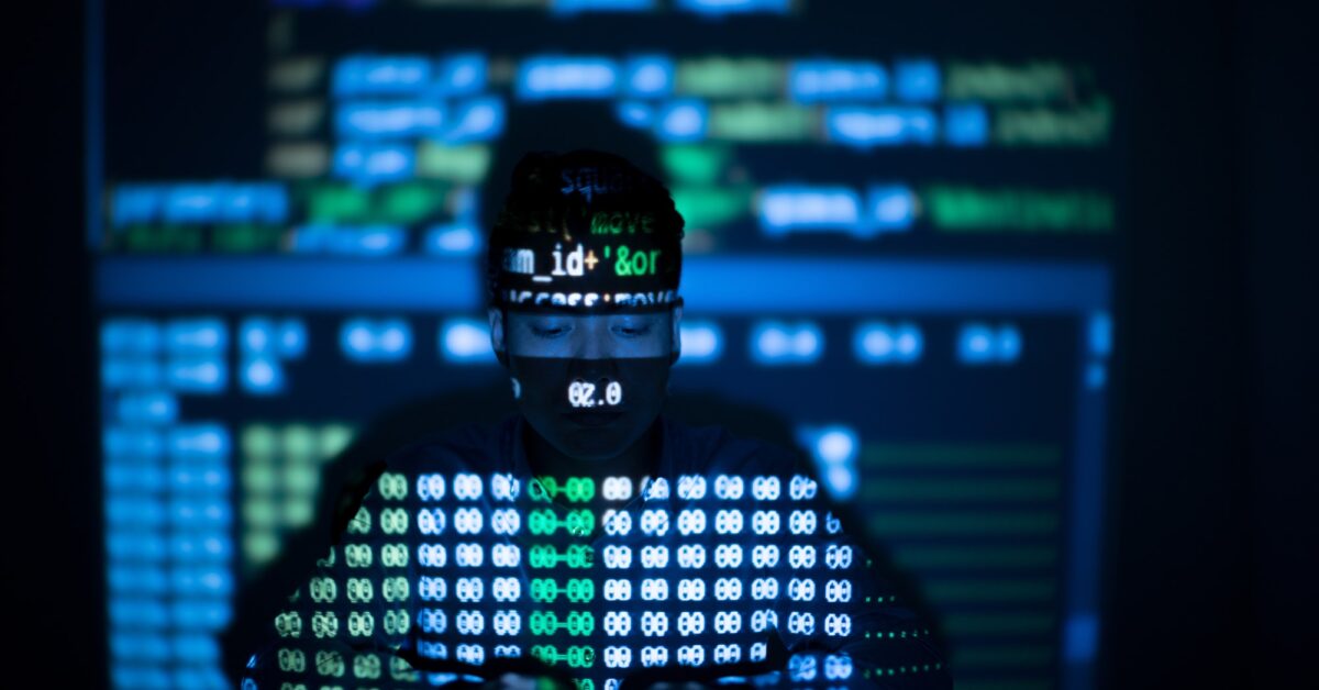 Anonymous hacker in glowing computer interface, scanning for sites that have no security headers to hack.